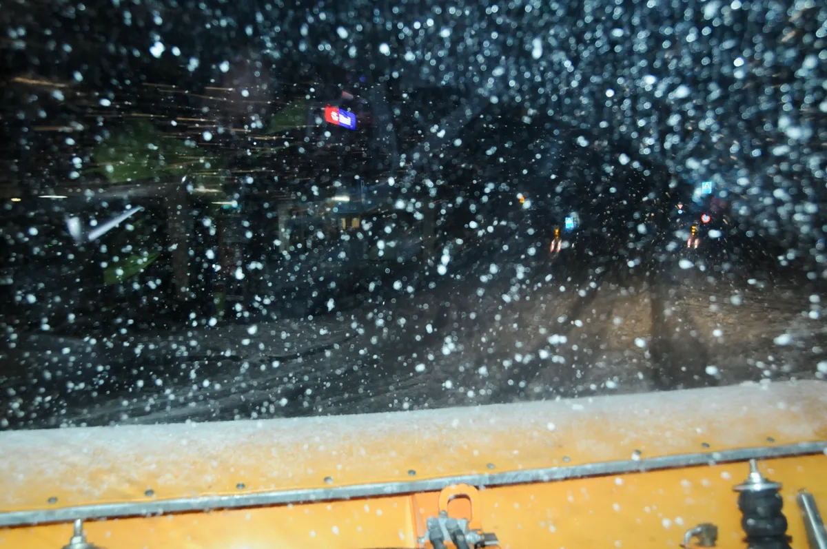 Man sieht einen verschneiten Morgen durch das Winterdienst-Fahrzeug.